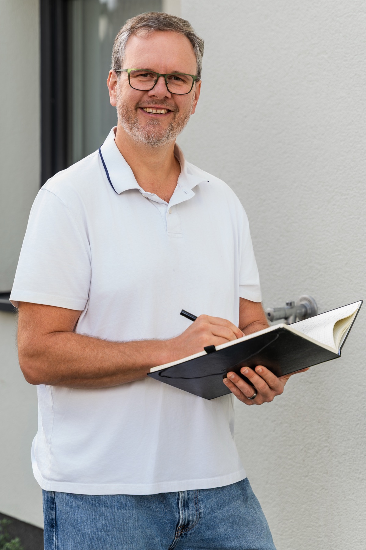 Porträt von Christian Persch mit Aufnahmeunterlagen vor einem Wohngebäude